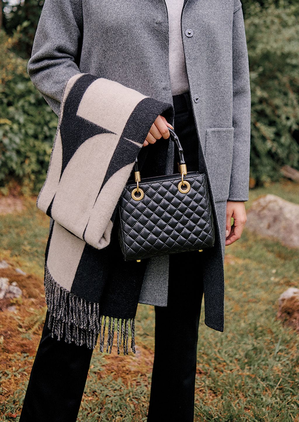 Shot of a woman in holding black handbag and scarf.