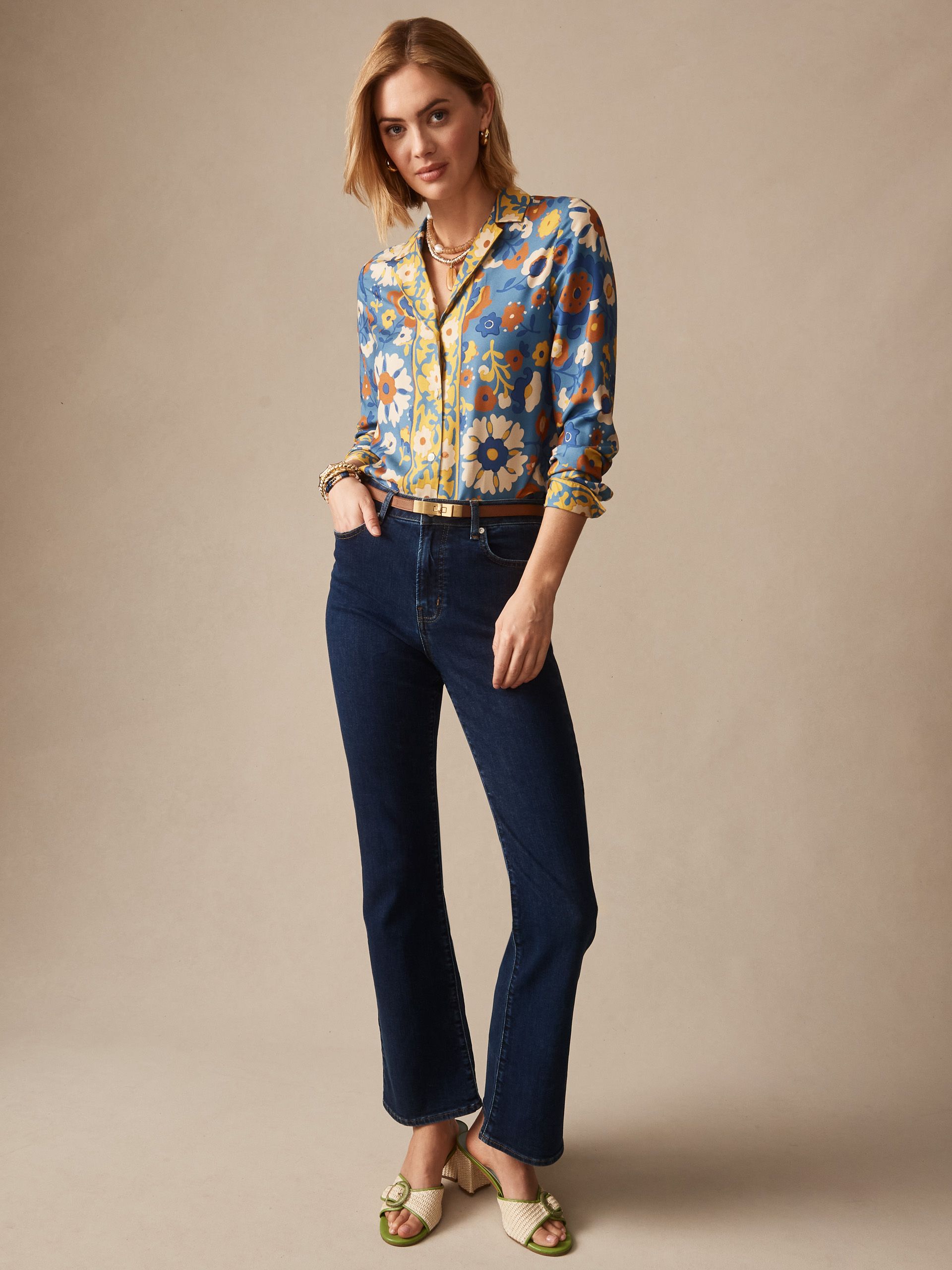 Model wearing floral blouse and denim jeans with heels. 