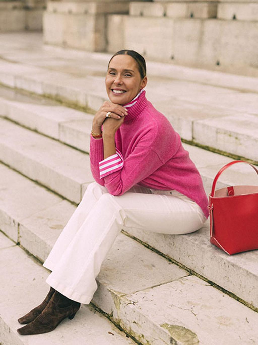 Filipa sitting on outside stairs in pink turtleneck and white jeans Filipa sitting on outside stairs in pink turtleneck and white jeans