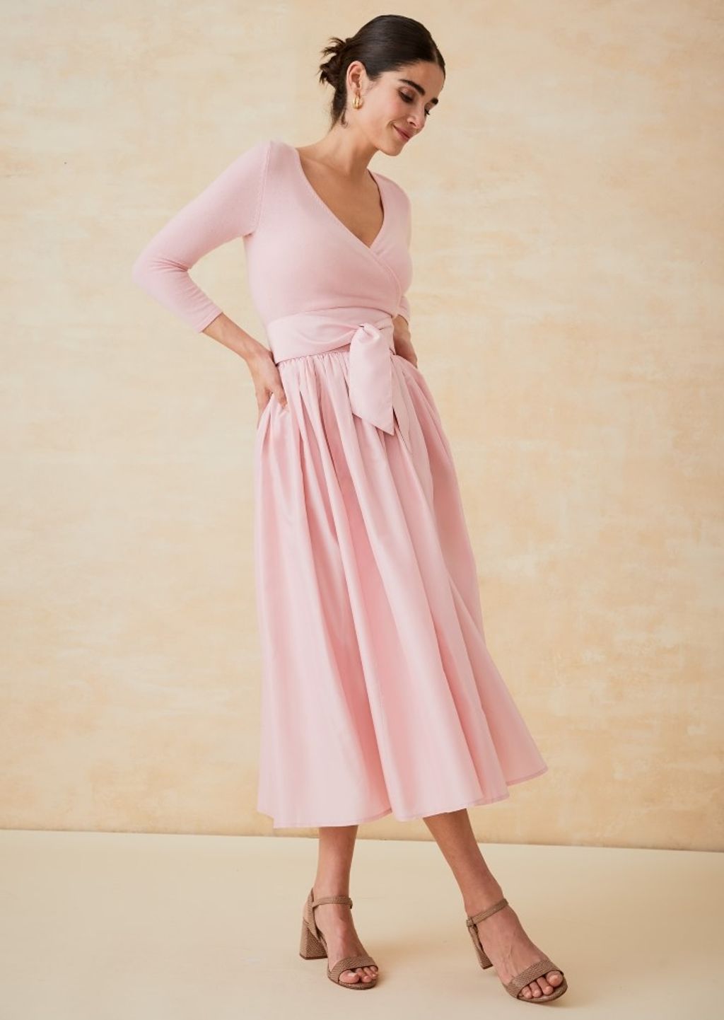 woman wearing a light pink wrap sweater and a pink taffeta ball skirt