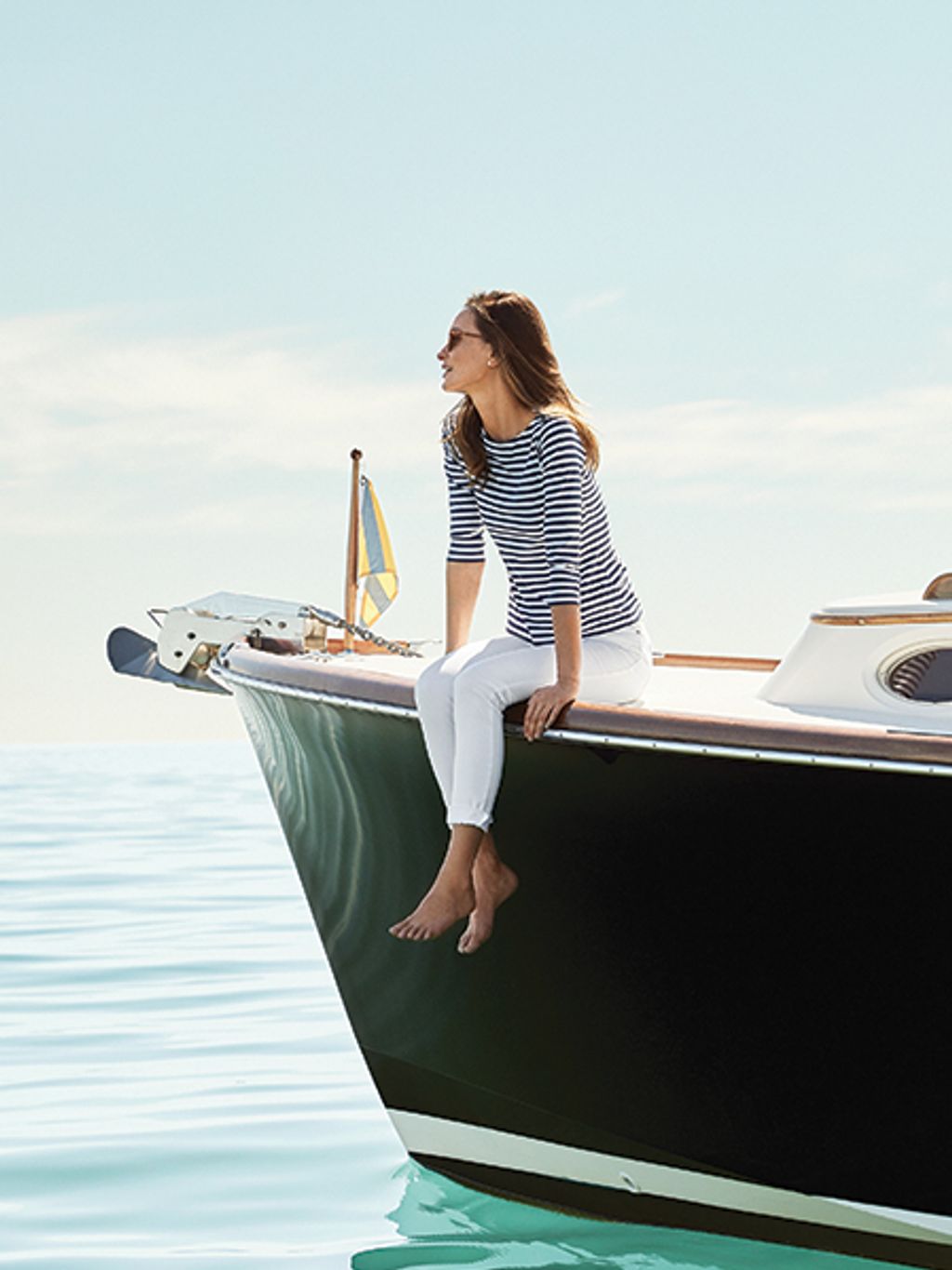 Model in striped tee and white denim on a boat