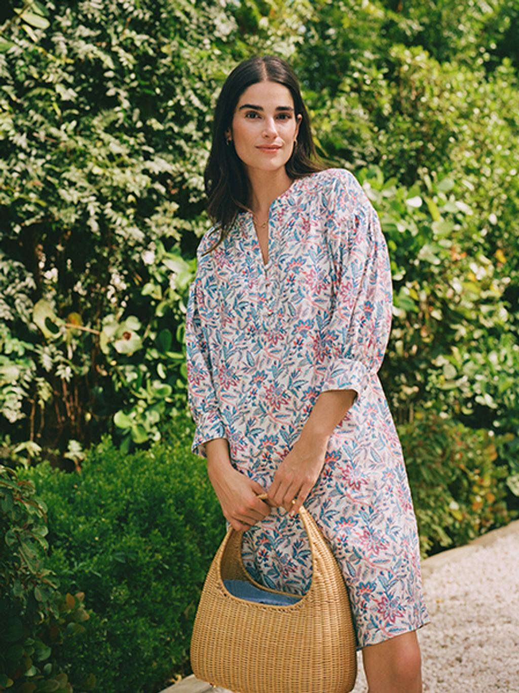 Model wearing floral shirtdress and wicker tote.
