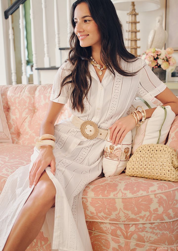 woman outside wearing beige knit wrap and white pants and white top