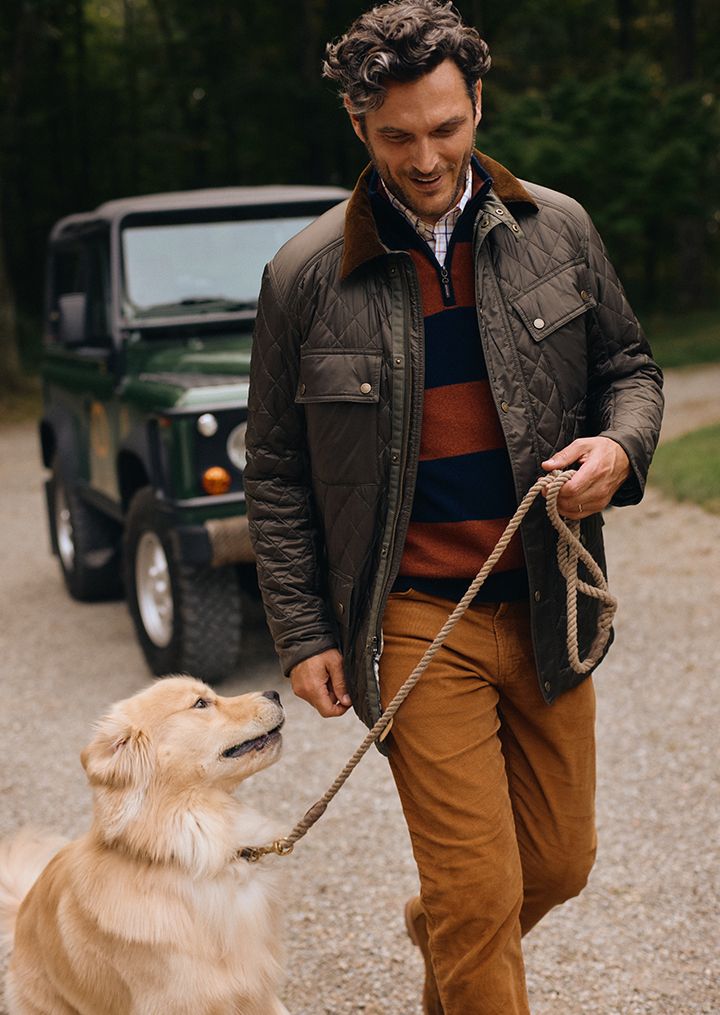 man walking outside with golden retriever wearing olive quilted jacket