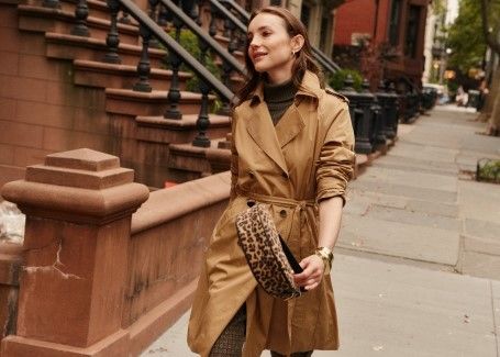 woman walking down city street wearing classic khaki trench