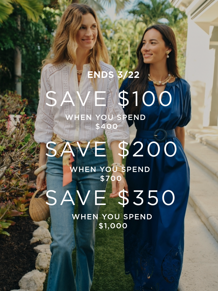 two women walking outside, one wearing white eyelet blouse and denim jeans, the other wearing navy puff sleeve long dress with cinch belt