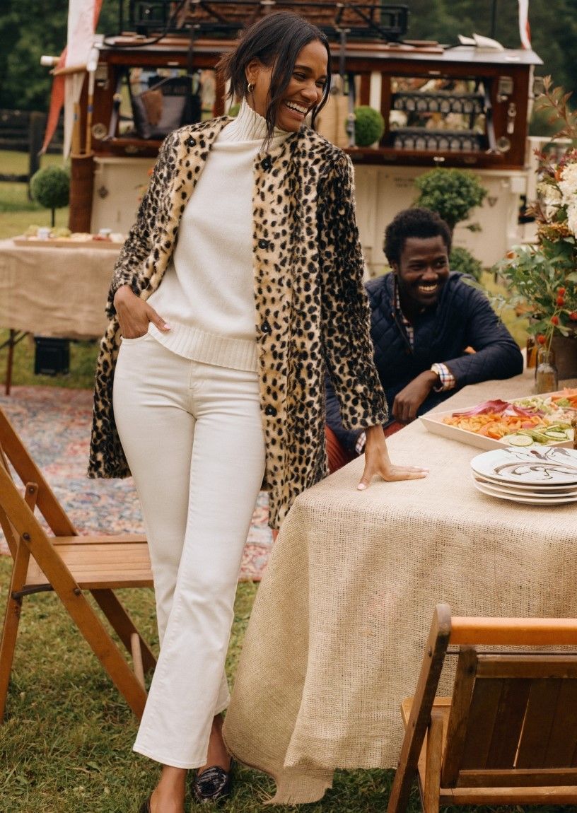 woman wearing cream flare jeans a cream cashmere turtleneck and a leopard faux fur coat