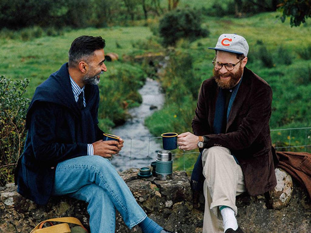 Manish and Jamie sit on a small rock wall overlooking a creek. Manish is wearing the Corduroy Suffolk in Navy and Jamie is wearing the Corduroy Suffolk in Brown