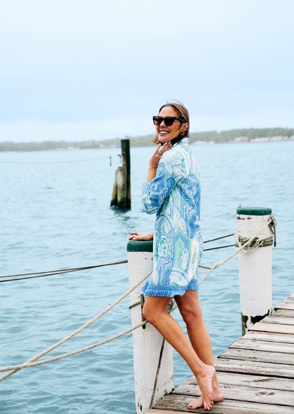 woman wearing blue multi color paisley coverup dress on pier overlooking water