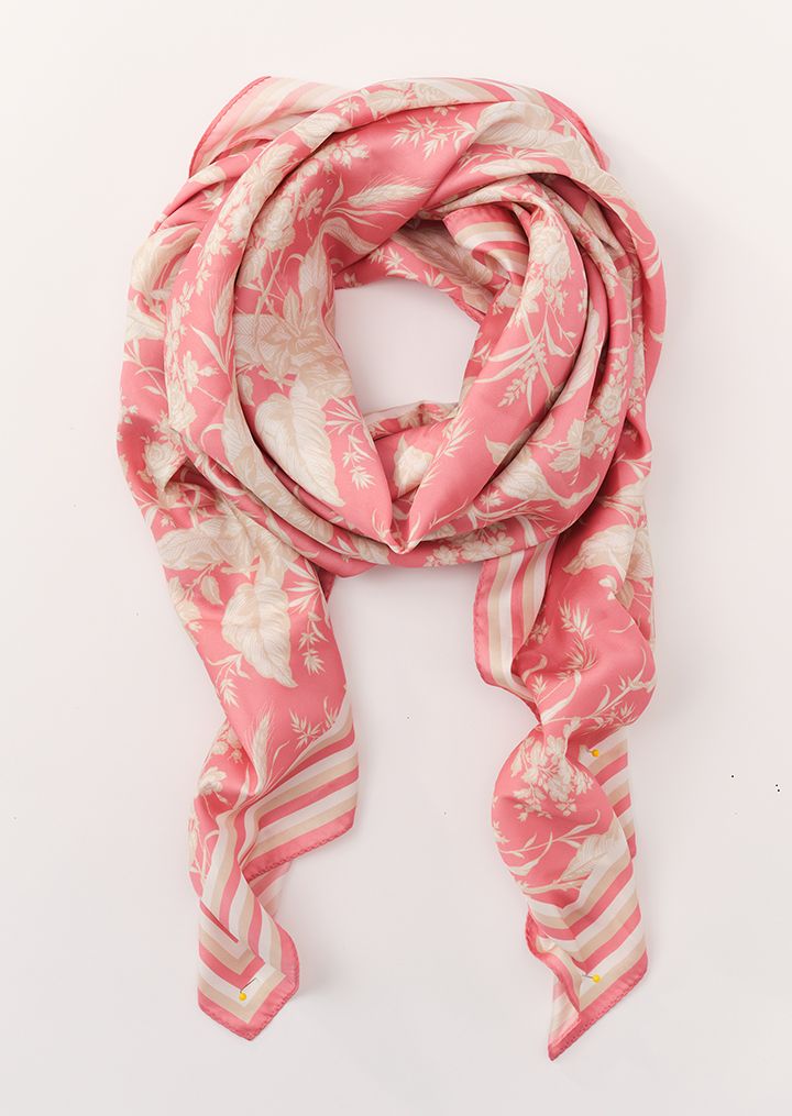 A pink scarf with a light botanical and striped pattern, draped on a white surface.