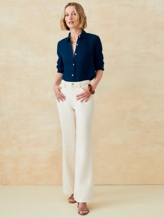 woman wearing egret white wideleg jeans and a navy button down shirt