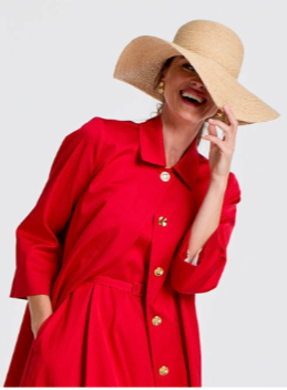 Smiling woman in a red outfit and wide-brimmed straw hat.
