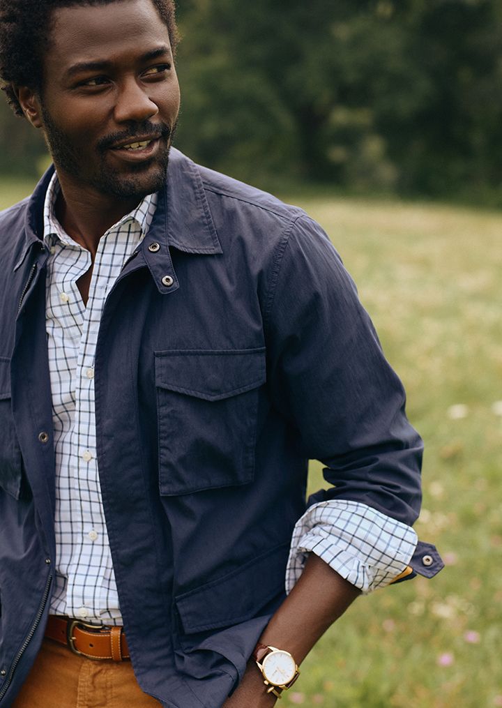 man in a field wearing navy lightweight nylon jacket