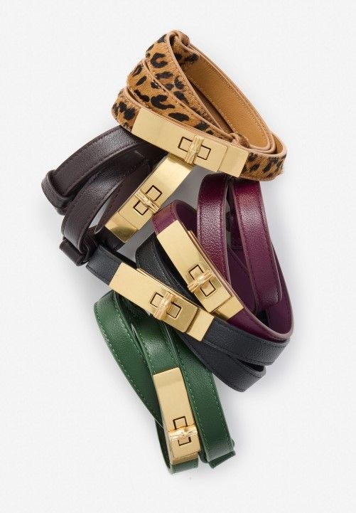 a group of womens skinny leather belts with brass turnlock hardware
