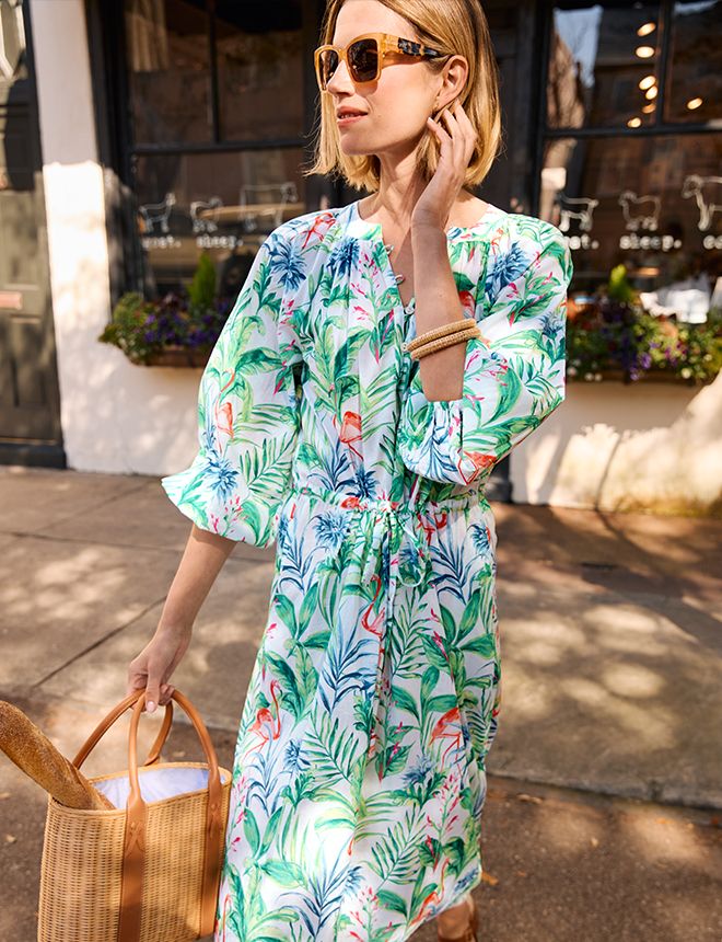 woman standing outside wearing white long flowy dress with botanical pattern