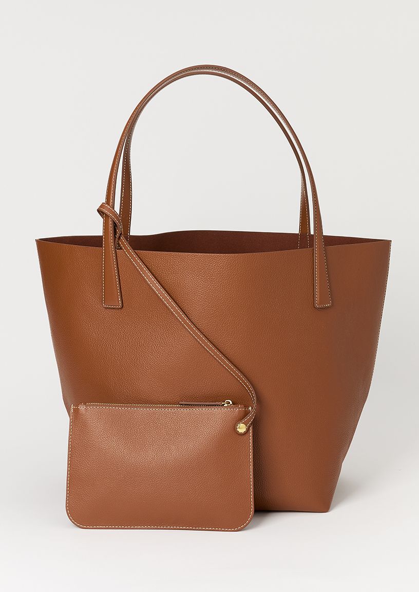 woman outside by citibike, wearing navy pinstripe trouser, crisp blue button down shirt and tan cardigan layered over her shoulders