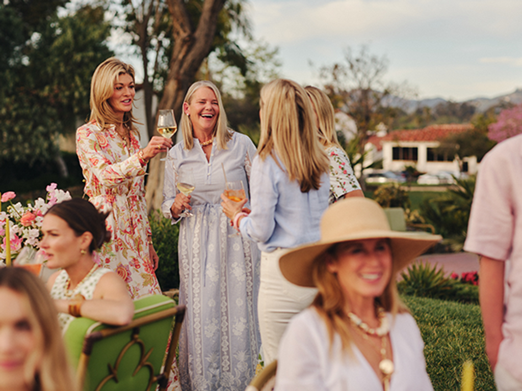 A group of women socializing and laughing at an outdoor party.