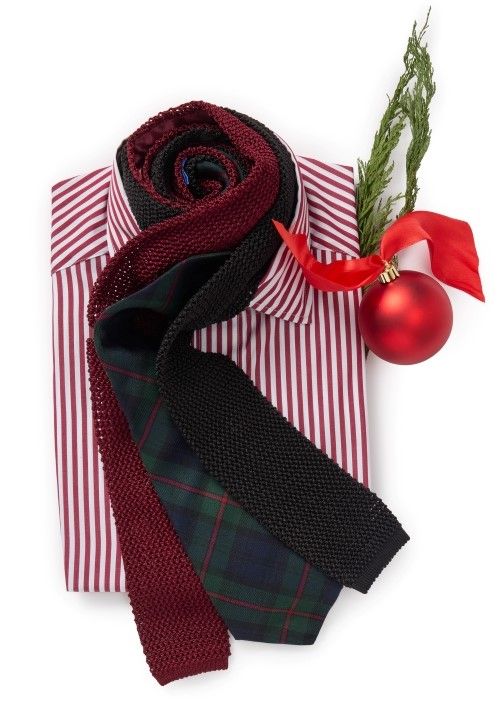 mens red and white striped shirt folded and flat with ties laid out around neck and red ornament positioned next to it