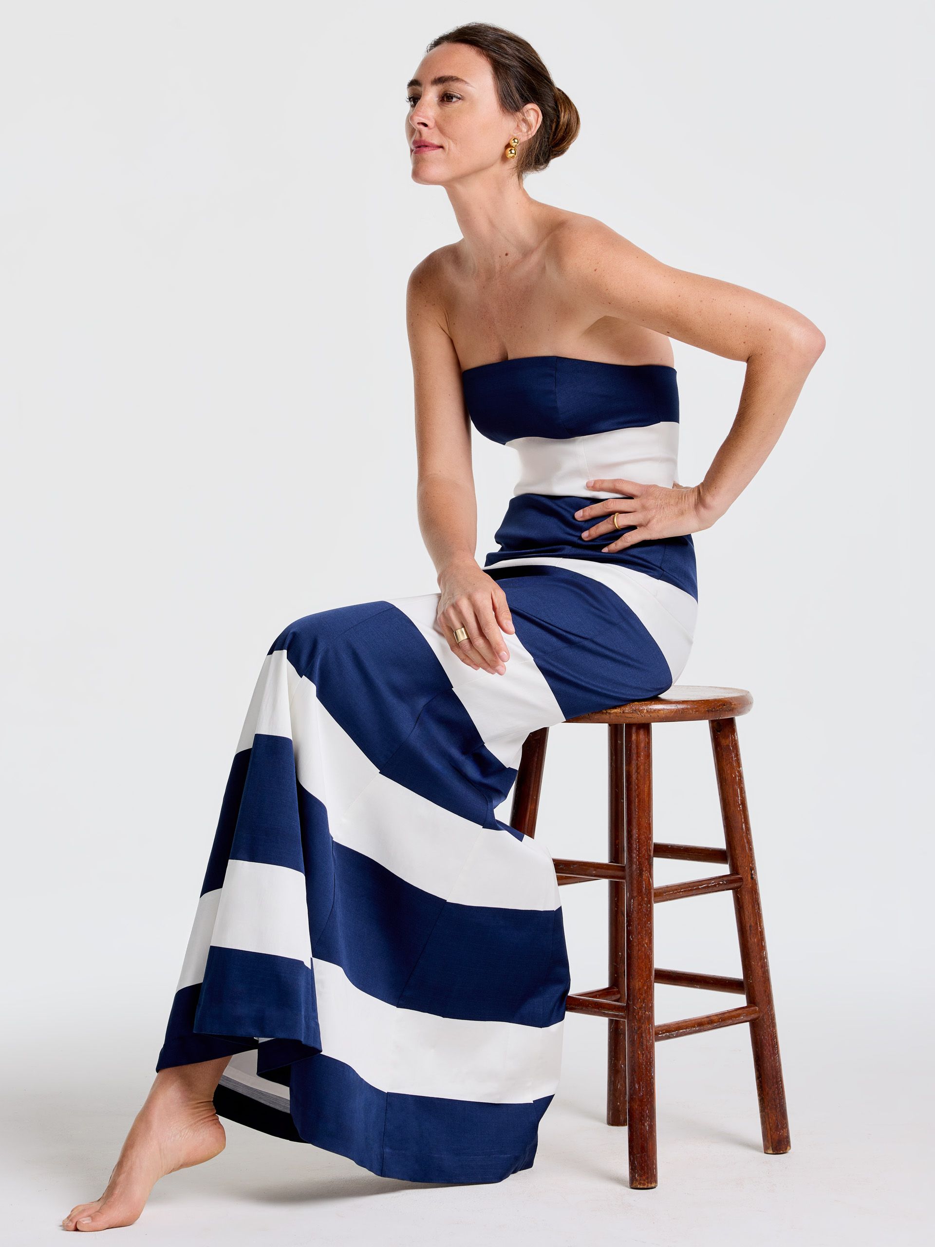 A woman in a navy blue and white striped strapless gown and a white bolero jacket.