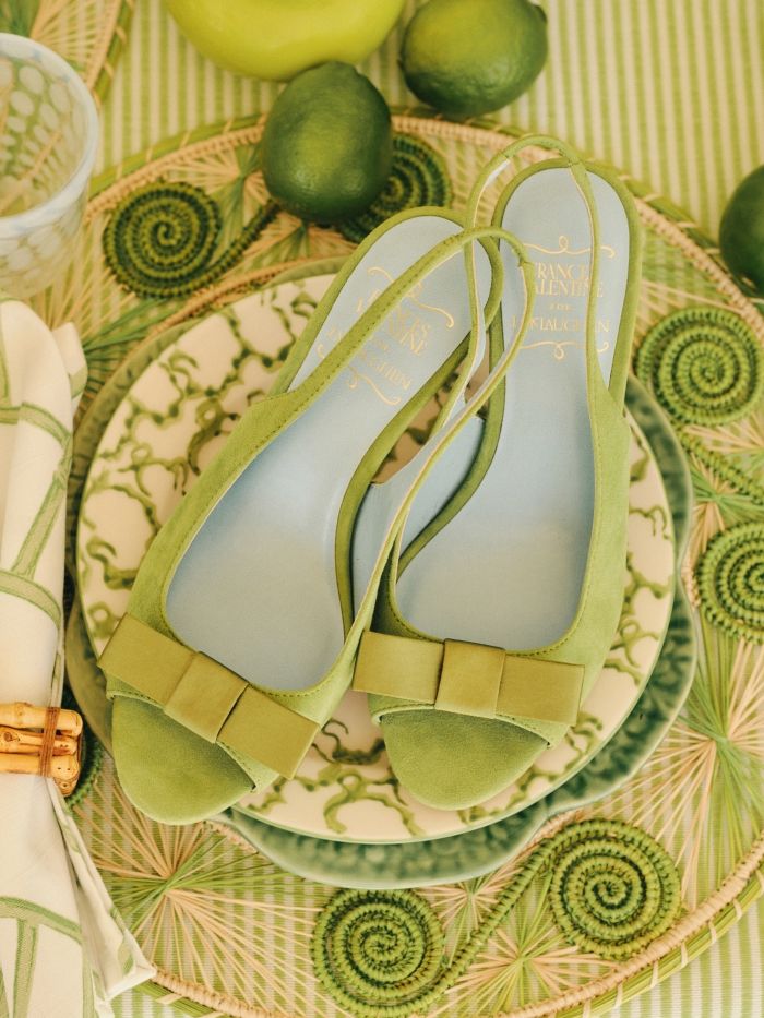 womens light green suede peep toe heels with bow detail positioned atop a green theme tabletop
