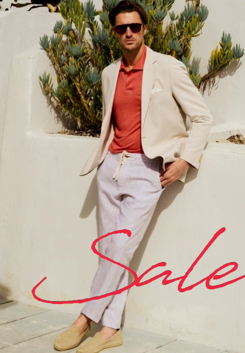 man standing against stucco wall outside in tan blazer and salmon knit polo with SALE messaging across image