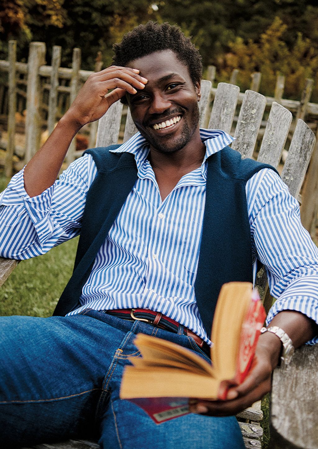 Male model modeling wearing button down shirt with sweater around shoulders 