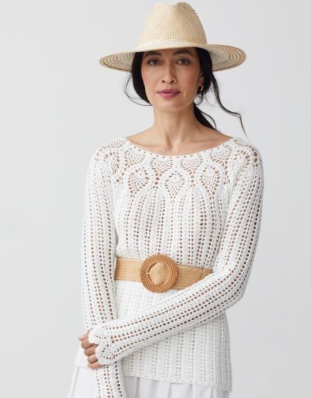 woman standing posed in white crochet sweater paired with grasscloth belt and raffia hat