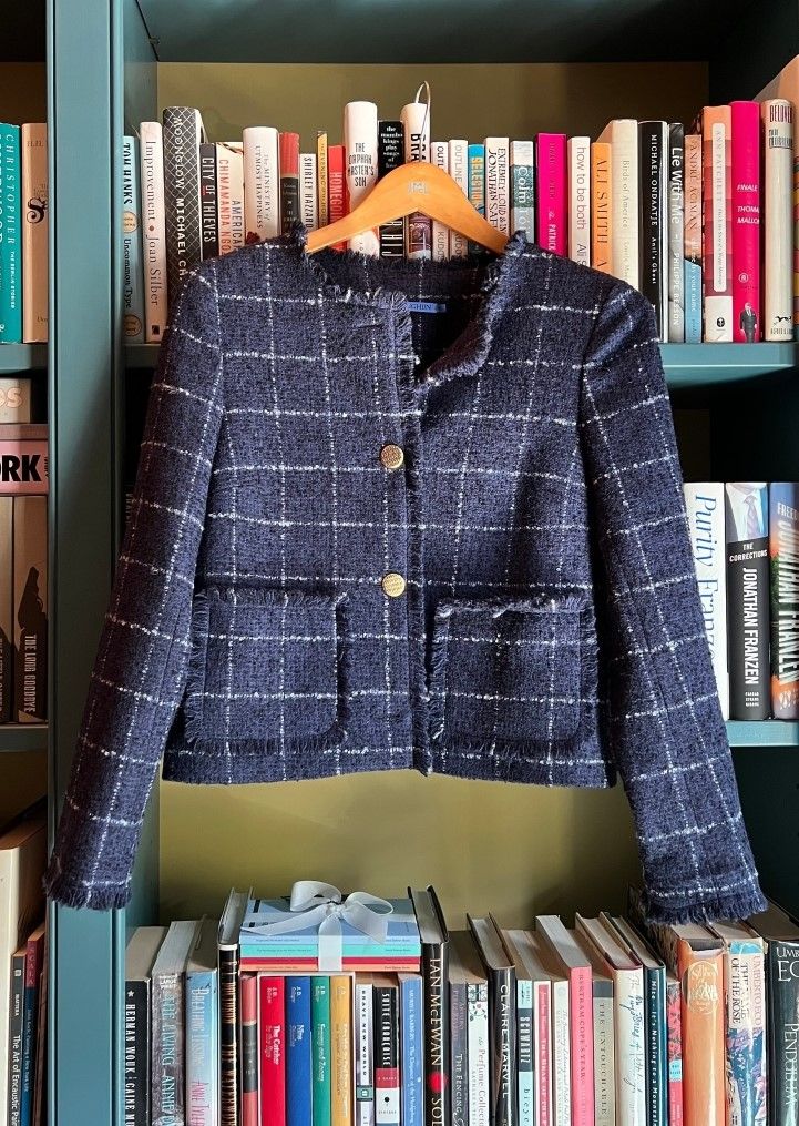 denim blue tweed windowpane jacket hanging in front of bookshelf