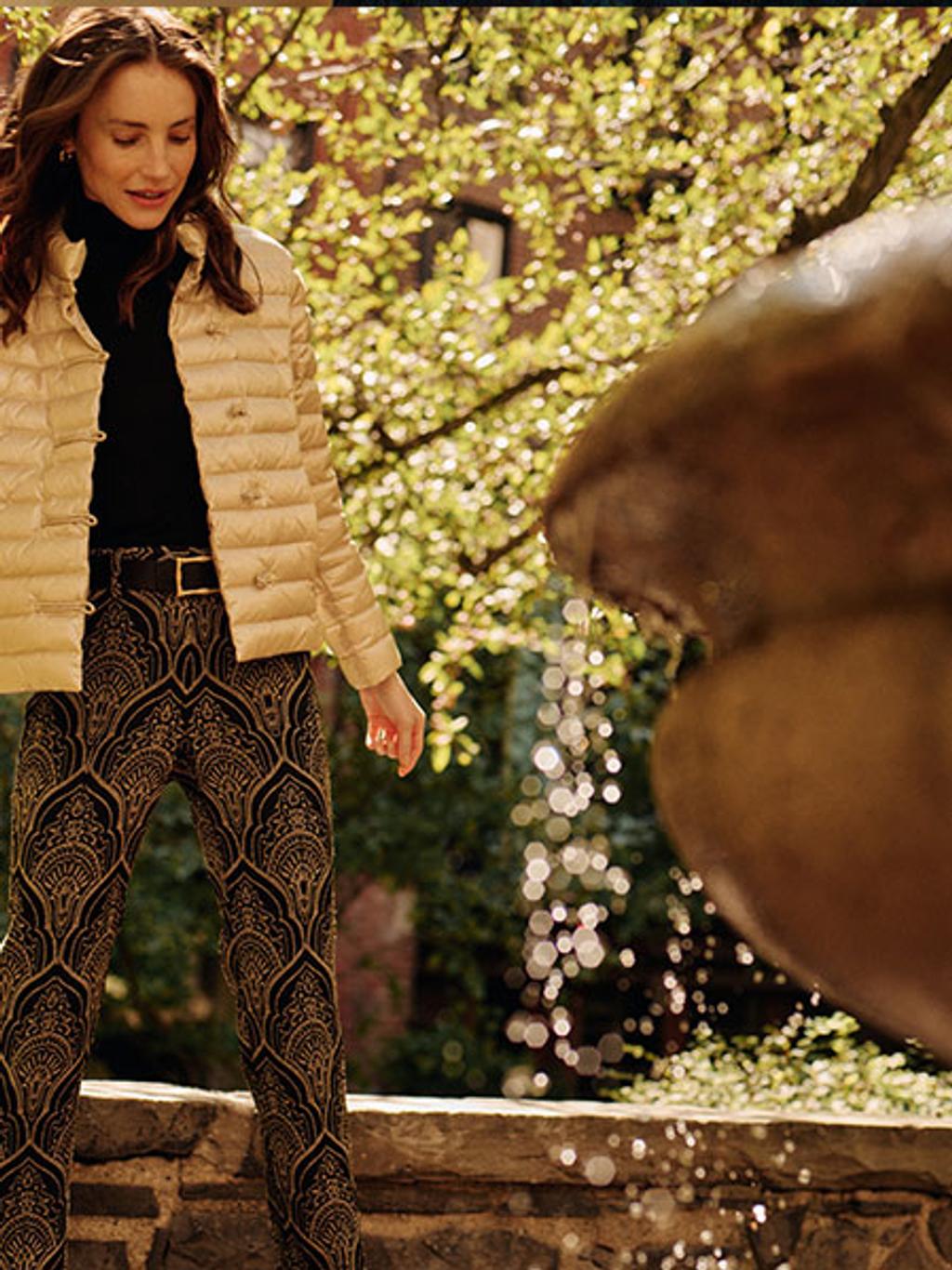 Model wearing champagne puffer jacket with black turtleneck and jacquard pants Model wearing champagne puffer jacket with black turtleneck and jacquard pants