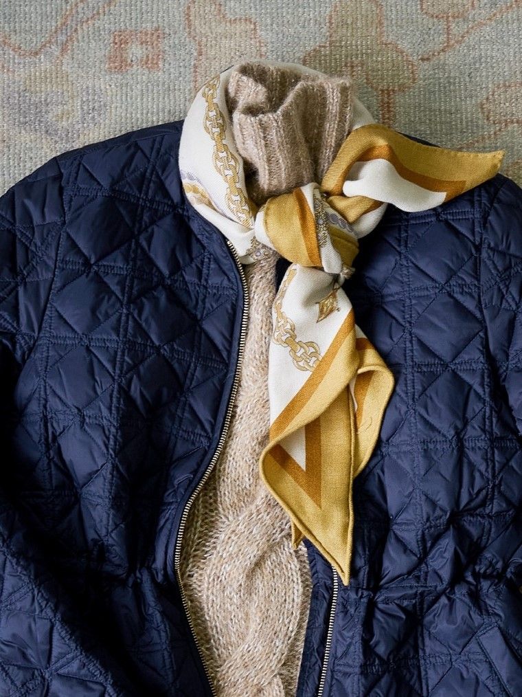close up image of printed scarf tied around cable sweater neck