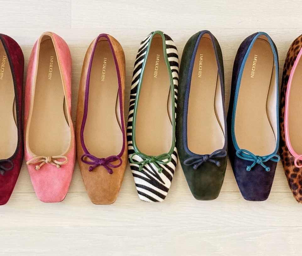 A row of colorful ballet flats, including solid colors, zebra print, and leopard print, most with small bows.