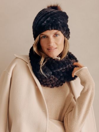 beauty shot of woman with matching faux fur hat and neckwarmer over beige sweater and coat