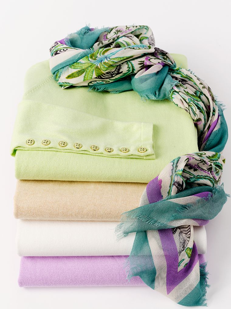 image stack of cotton sweaters in various colors with printed scarf on top. 