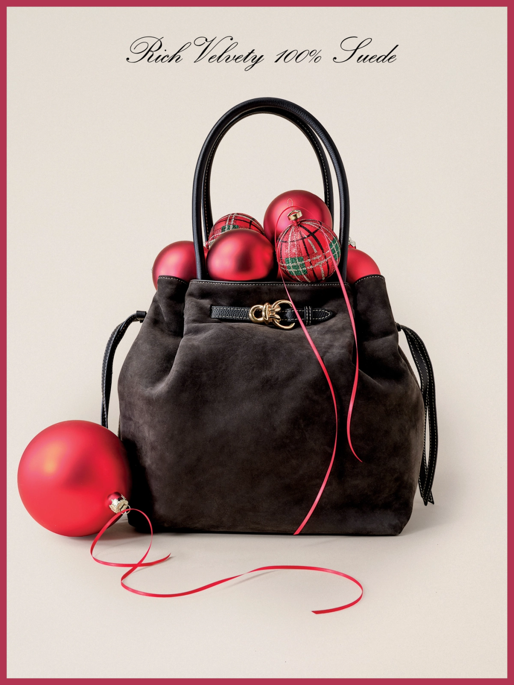 Charcoal suede handbag overflowing with red and plaid Christmas ornaments and ribbons, with an ornament beside it. Text: "Rich Velvety 100% Suede."