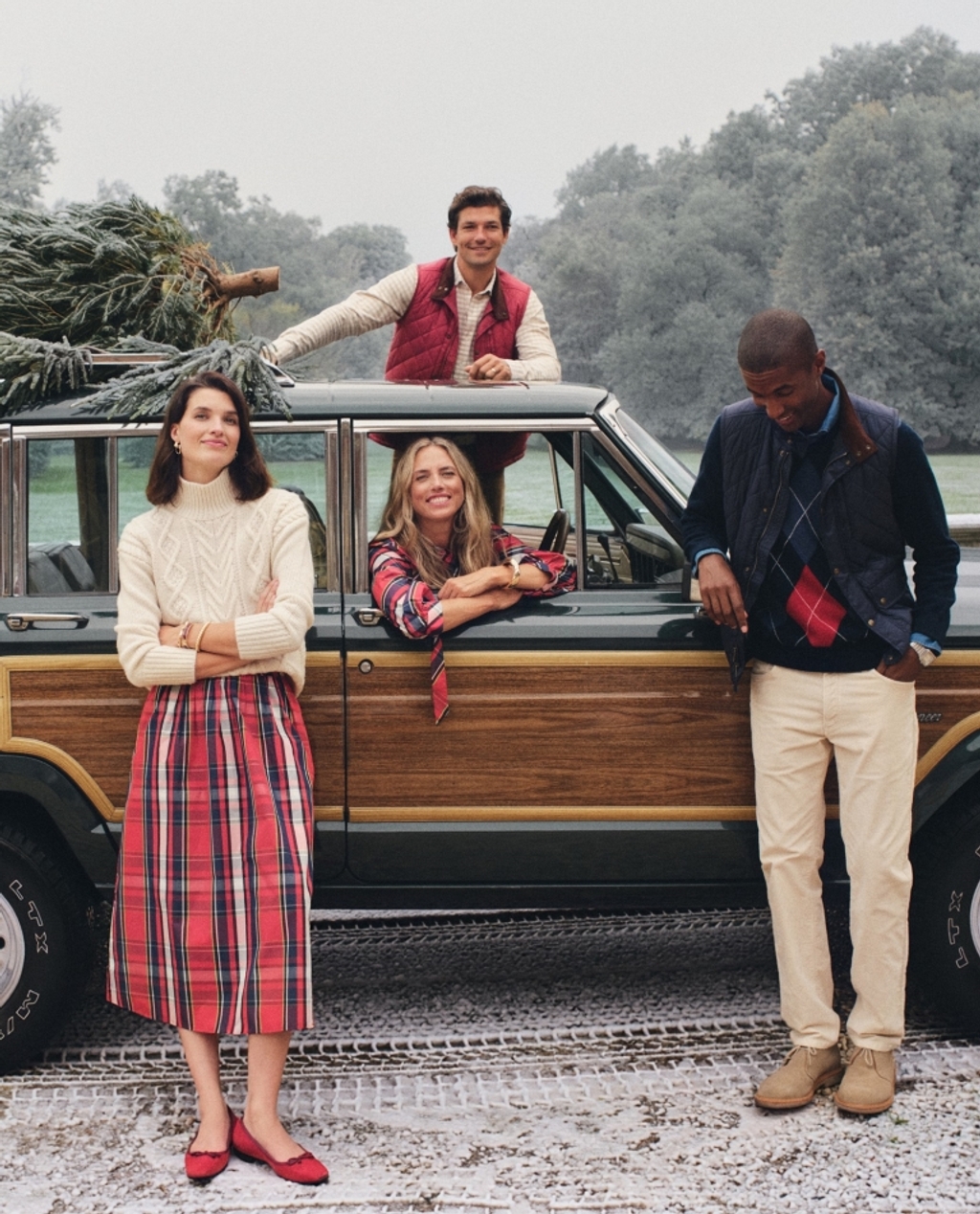 Four people in winter fashion with a Christmas tree on a vintage wood-paneled SUV.