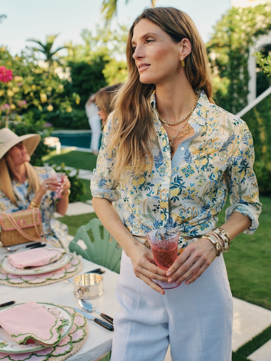 woman standing outside at a party wearing amalfi coast pattern button down shirt
