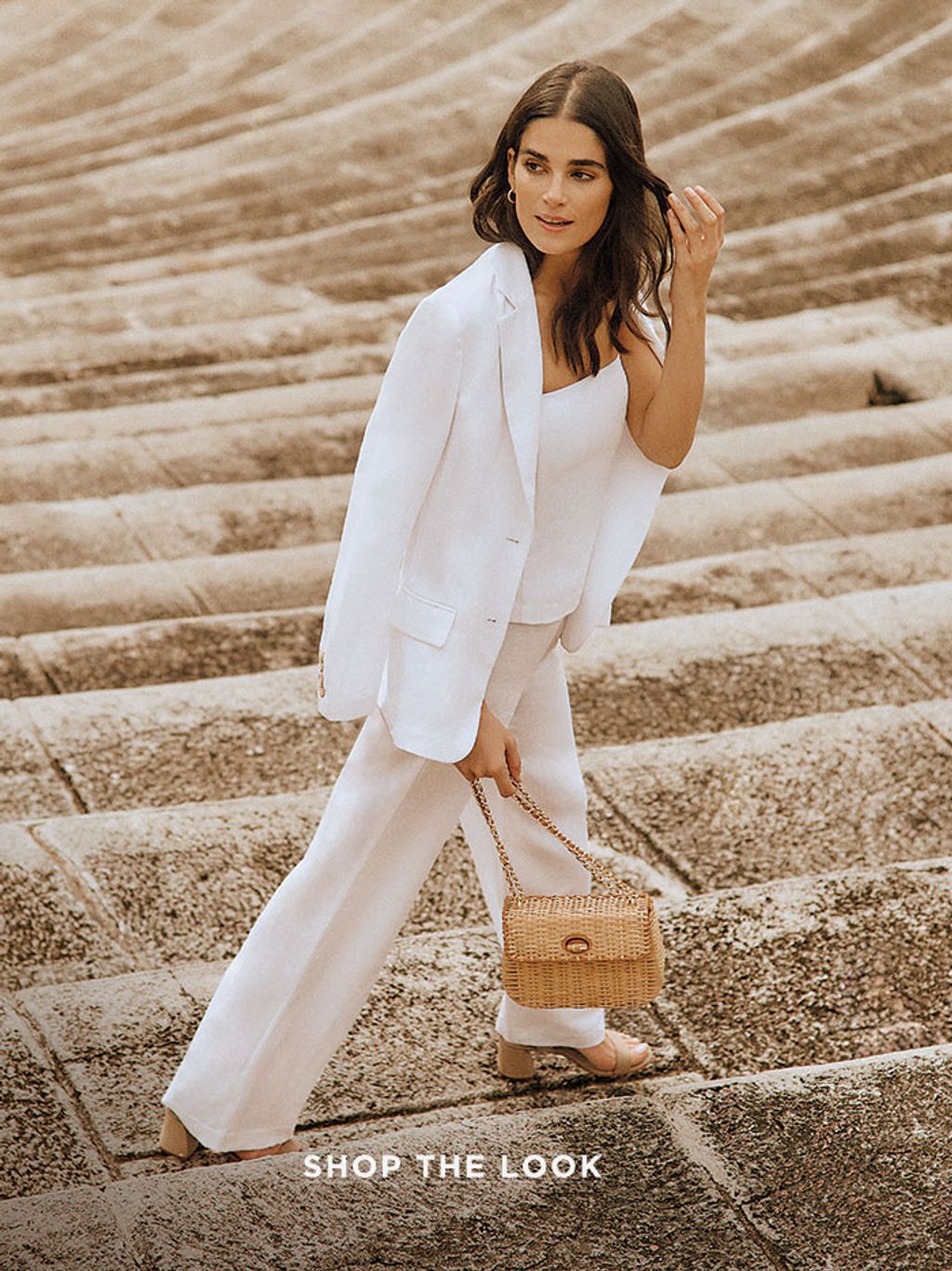 woman standing on stone steps wearing a white suit