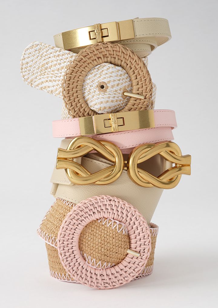 A stack of beige, white, and pink belts with gold and woven buckles.s