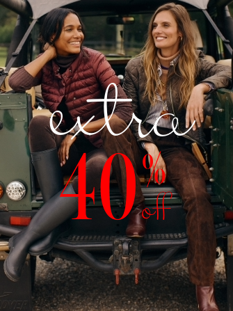 two women seated on back of truck in puffer jackets