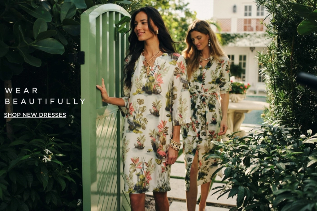 two women walking thru gate from pool wearing floral printed dresses