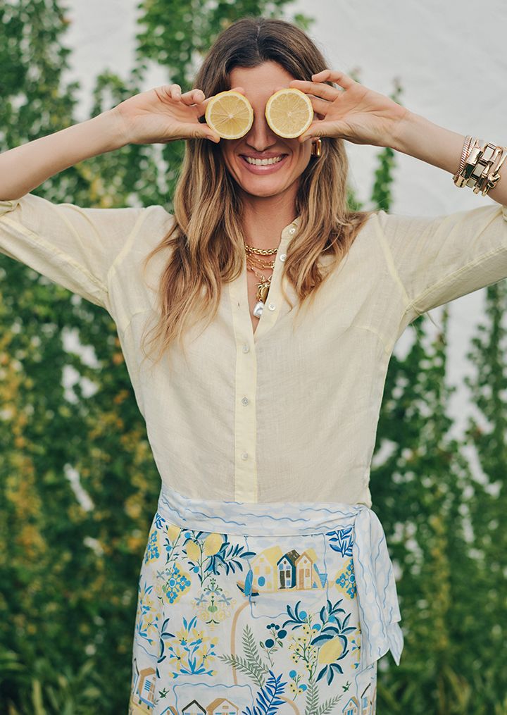woman outside wearing beige knit wrap and white pants and white top
