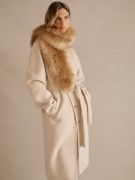 woman wearing light beige belted coat with tan faux fur stole scarf
