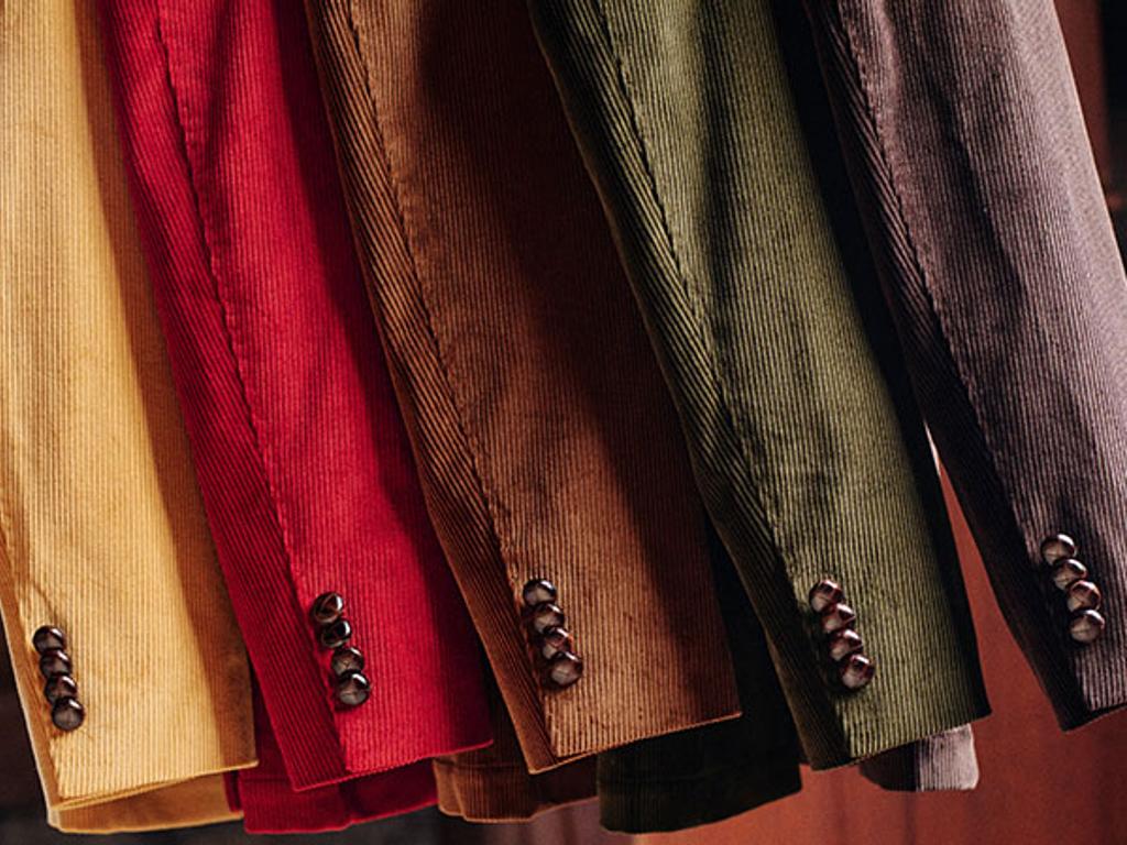 A collection of hanging corduroy Suffolk jackets showing the texture of the Brisbane Moss cloth as well as the traditional leather buttons