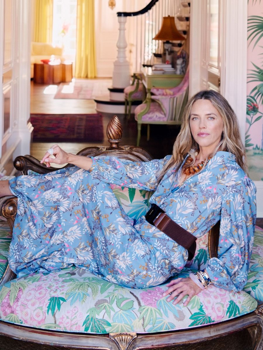 woman lounging on floral large ottoman wearing blue floral printed silky dress