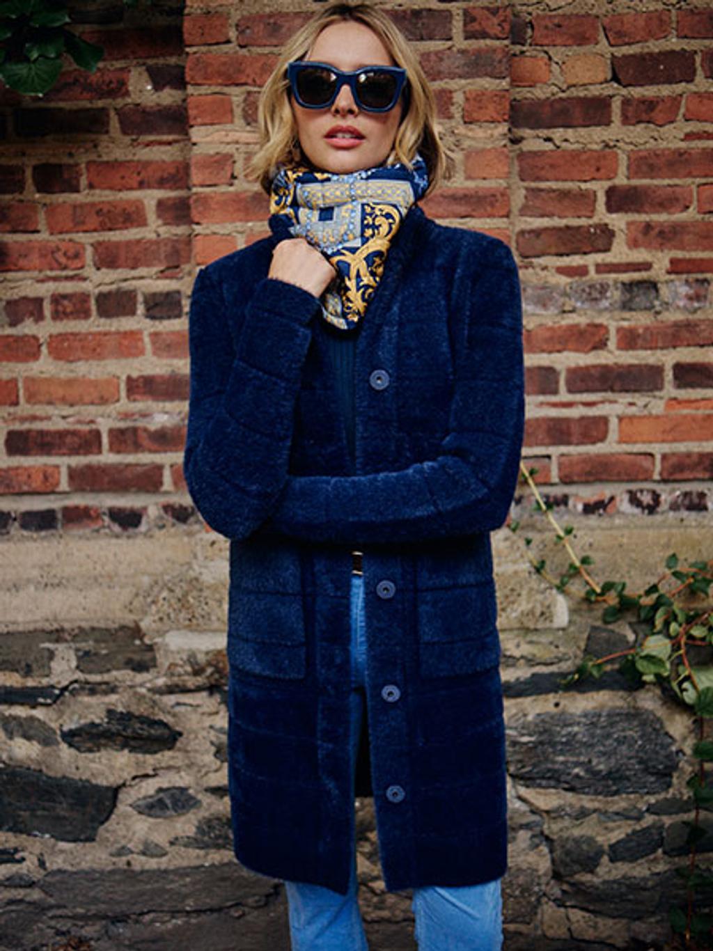 Model wearing sweater coat, printed snood, and velvet jeans outside Model wearing sweater coat, printed snood, and velvet jeans outside