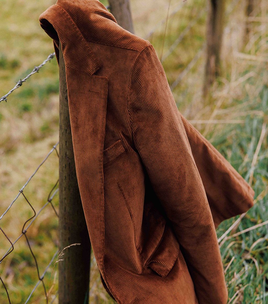 Corduroy sport coat hanging on wooden pole