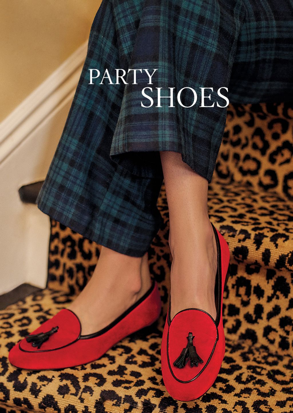 Close up shot of women's red velvet loafers and navy and green plaid pants.