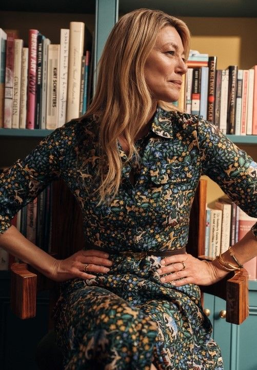 woman sitting inside in a study wearing a black multi color patterned silky shirtdress