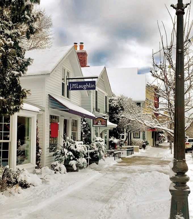 snow covered street with J.McLaughlin store signage hanging outside white panneled store