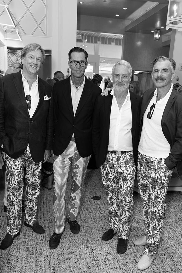 Black and white photo of four men in dark blazers and patterned trousers standing together.